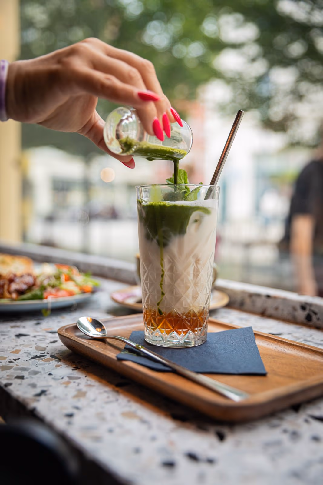 Matcha wird in ein hohes Glas mit Milch gegossen